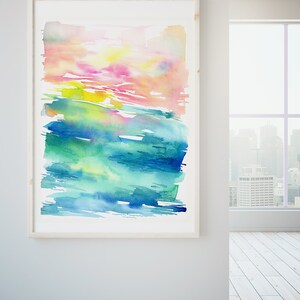 K&ouml;nnte beinhalten: Abstraktes Aquarellbild in einem Holzrahmen. Das Bild zeigt eine Mischung aus rosa, gelben, gr&uuml;nen und blauen Farbt&ouml;nen, die einen geschichteten und strukturierten Effekt erzeugen.