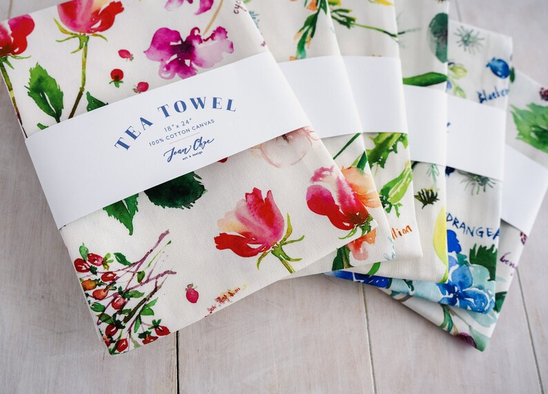 May include: Five tea towels with floral designs and names of the flowers printed on them. The towels are 18 inches by 24 inches and made of 100% cotton canvas. The brand name "Jean Oye" is printed on the label.