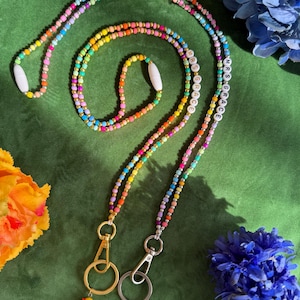 Puede incluir: Dos cordones de cuentas coloridas con detalles dorados y dijes de patos de goma. Los cordones llevan el nombre "MRS GRACE" en cuentas blancas.