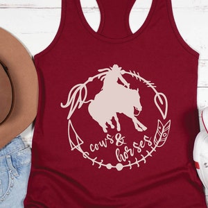 May include: A maroon tank top with a white silhouette of a woman riding a horse. The design includes the text "cows & horses" and a variety of decorative elements.