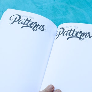 May include: Open book with blank pages and the text "Draw Your Patterns" on both sides of the spread.