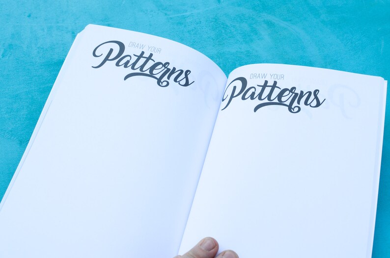 May include: Open book with blank pages and the text "Draw Your Patterns" on both sides of the spread.