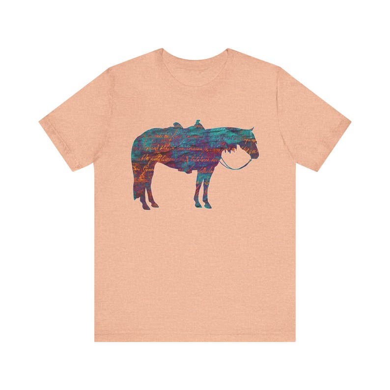 Op de afbeelding: Een lichtroze T-shirt met een kleurrijk silhouet van een paard met een zadel.