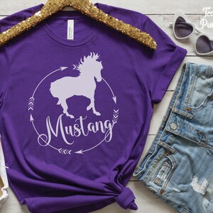 May include: Purple short-sleeved t-shirt with a white silhouette of a horse and the word "Mustang" in a circle with arrows.