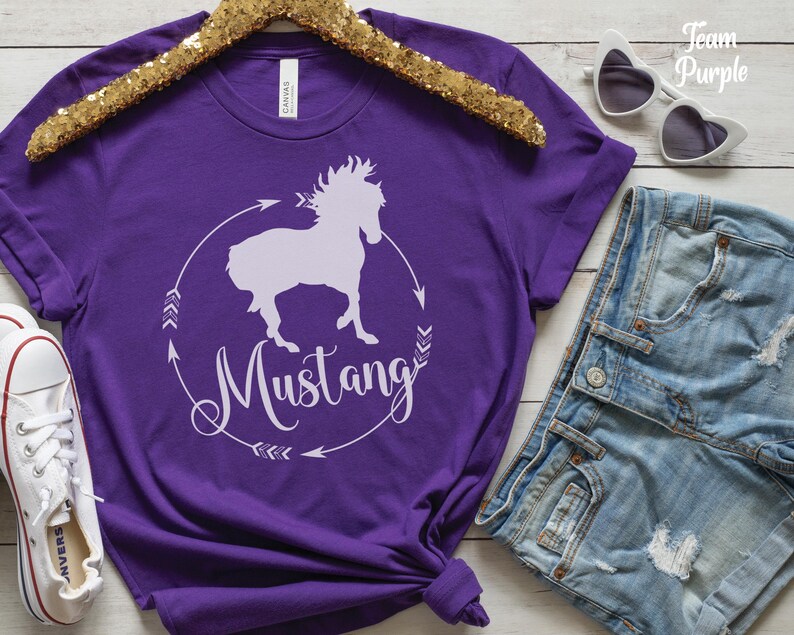 May include: Purple short-sleeved t-shirt with a white silhouette of a horse and the word "Mustang" in a circle with arrows.