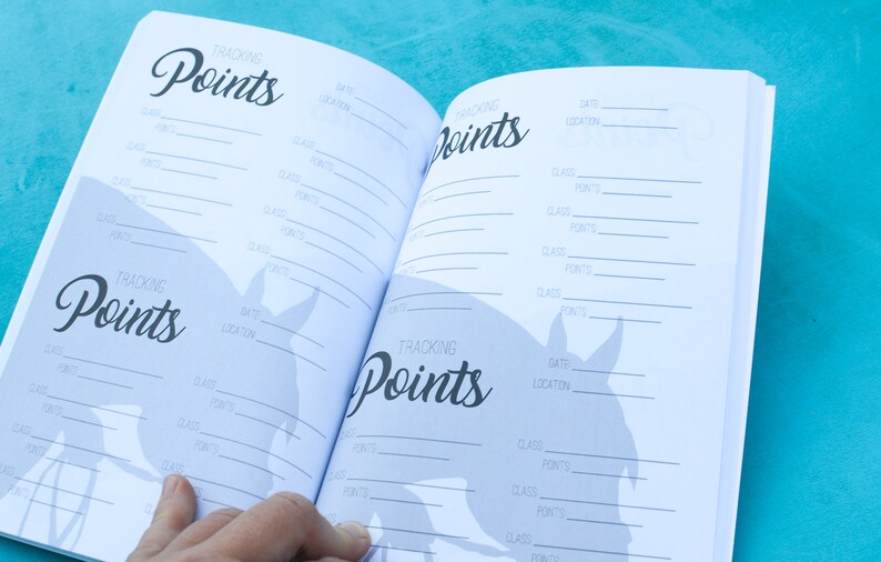May include: An open notebook with a horse silhouette on the cover. The pages are filled with lines for tracking points, dates, locations, and classes.