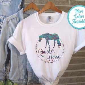 May include: White t-shirt with a turquoise and orange watercolor design of a quarter horse. The design includes the words "Quarter Horse" in a circle with arrows.