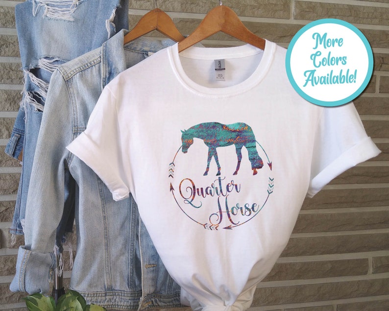 May include: White t-shirt with a turquoise and orange watercolor design of a quarter horse. The design includes the words "Quarter Horse" in a circle with arrows.