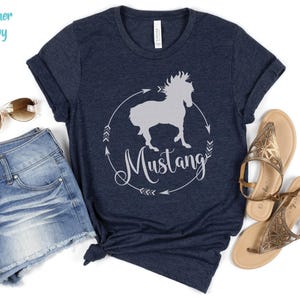 May include: A heather navy blue t-shirt with a white silhouette of a horse and the word "Mustang" in a circle.