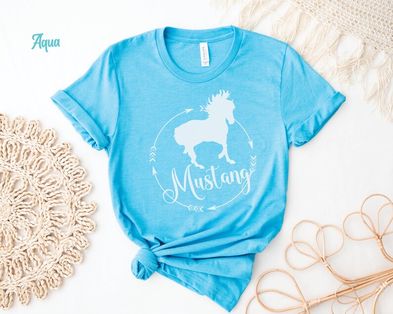 May include: A light blue t-shirt with a white silhouette of a horse and the word "Mustang" in a circle with arrows.