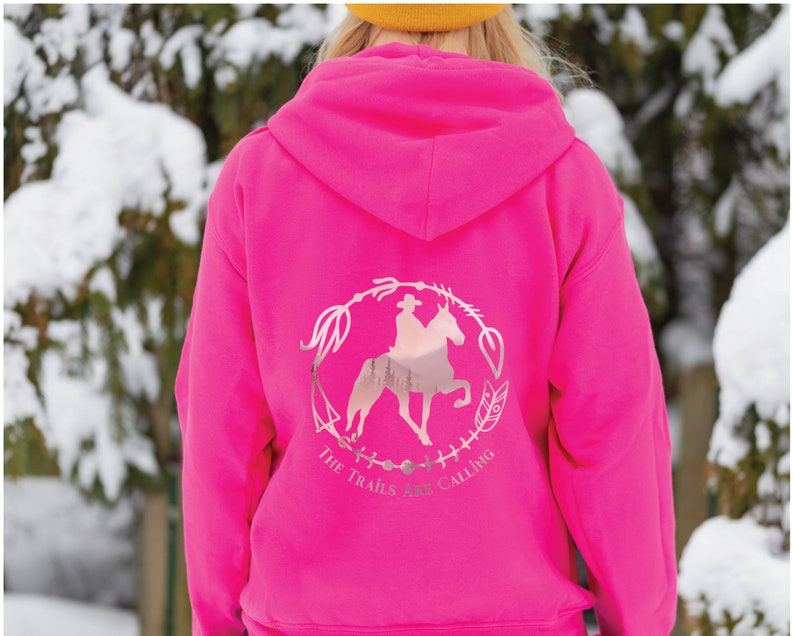 May include: A pink hoodie with a silver graphic of a person riding a horse with the text "The Trails Are Calling" on the back.