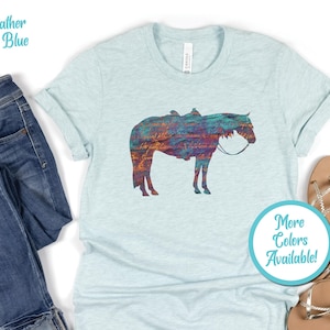 Op de afbeelding: Een hemelsblauw t-shirt met een kleurrijk silhouet van een paard. De tekst "Meer kleuren beschikbaar!" staat op een turquoise cirkel.