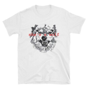 May include: White t-shirt with a black and white illustration of a wolf's face and the text "she's a wolf" in red.