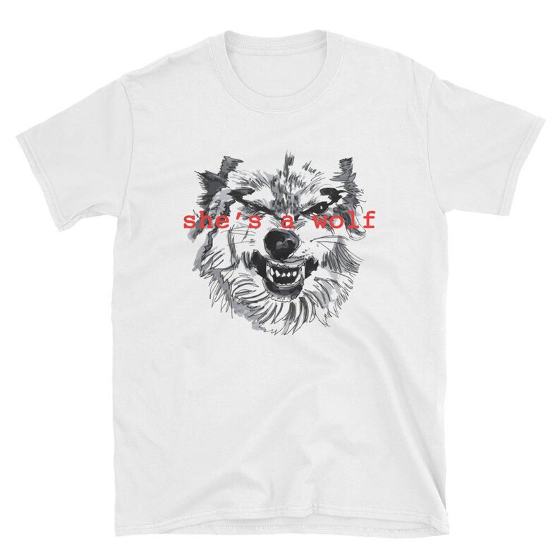 May include: White t-shirt with a black and white illustration of a wolf's face and the text "she's a wolf" in red.