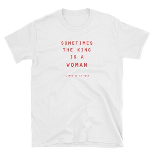 May include: White t-shirt with red text that reads "Sometimes the king is a woman - James de la Vega"