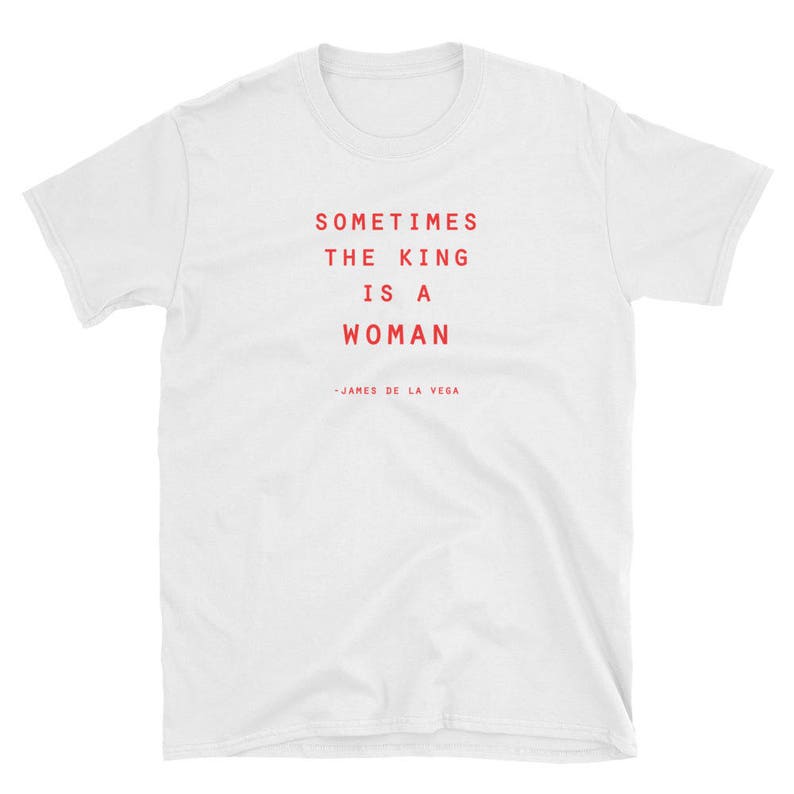 May include: White t-shirt with red text that reads "Sometimes the king is a woman - James de la Vega"