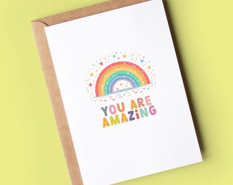 May include: A white card with a rainbow and the text "You are amazing" in colourful letters. The rainbow is surrounded by confetti and hearts.