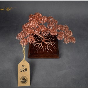 May include: A copper wire bonsai tree sculpture on a wooden base. The tree has a thick trunk and many branches. The sculpture is labeled with the number 528.