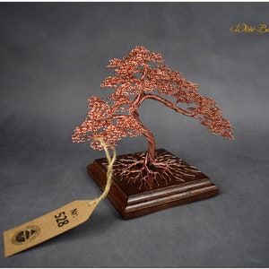 May include: A copper wire bonsai tree sculpture with a wooden base. The tree has a twisted trunk and branches with small copper beads. The base is a dark brown square with a label that says "No. 528".