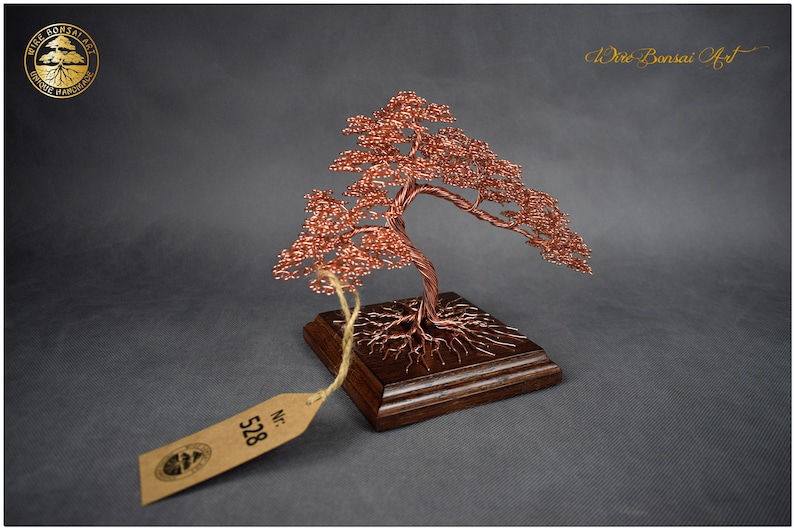May include: A copper wire bonsai tree sculpture with a wooden base. The tree has a twisted trunk and branches with small copper beads. The base is a dark brown square with a label that says "No. 528".