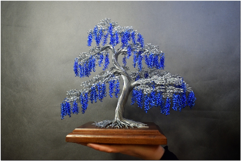 May include: A wire sculpture of a tree with blue beads representing blossoms. The tree is on a wooden base.