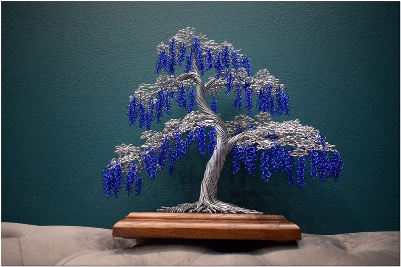 May include: A wire sculpture of a tree with blue and silver wire. The tree is on a wooden base.