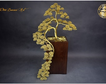 May include: A handcrafted wire bonsai tree sculpture in gold, mounted on a dark wooden block. The tree's intricate branches and leaves cascade gracefully. The sculpture is a unique piece of art.