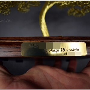 May include: A gold wire tree sculpture on a wooden base with a brass plaque that reads "Dla z okazji 18 urodzin od".