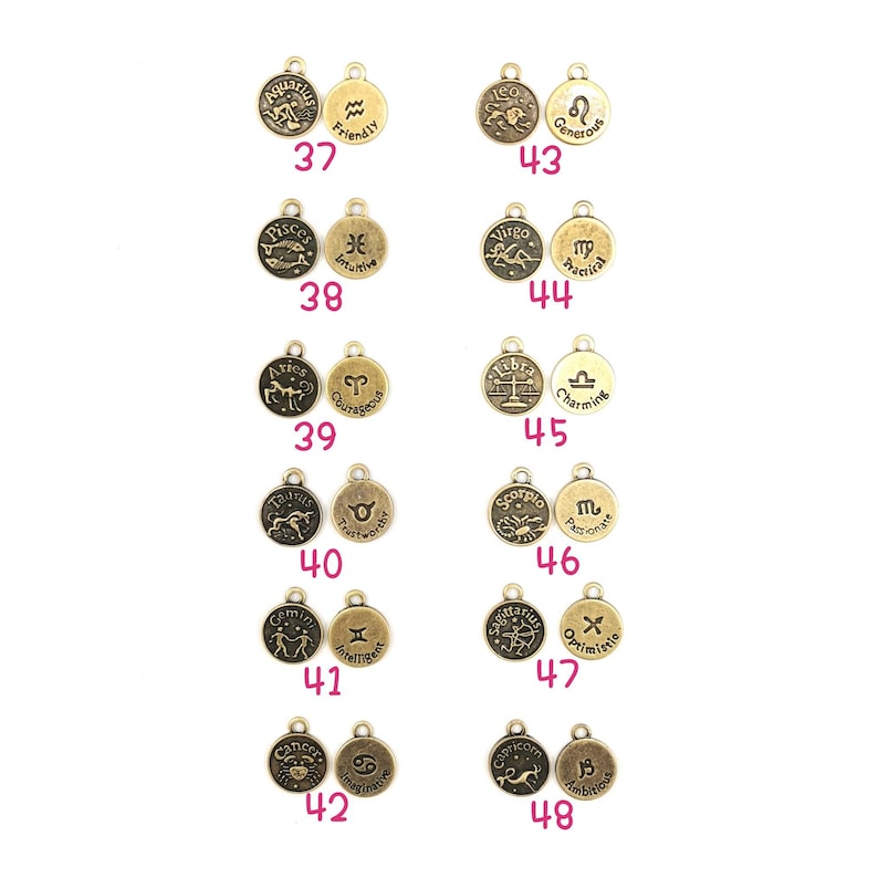 May include: A collection of antique gold-colored zodiac charms. Each charm features a zodiac symbol and a corresponding word, such as "Friendly" for Aquarius and "Intuitive" for Pisces. The charms are numbered from 37 to 48.