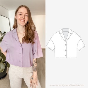 May include: A purple cropped button-down shirt with a collar and short sleeves. The shirt is shown on a model wearing it with grey pants. The image also includes a line drawing of the shirt.
