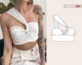 Pode incluir: Top branco de um ombro só com um detalhe de torção na frente. O top é feito de um tecido macio e elástico e tem um caimento relaxado.