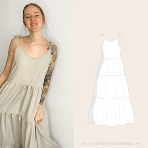 May include: A light beige tiered maxi dress with thin straps and a V-neckline. The dress has a relaxed fit and is shown on a model with a tattoo on her arm. The dress is shown next to a line drawing of a similar dress.
