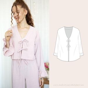 May include: A light pink, long-sleeved top with a deep V-neckline and a tie at the front. The top has ruffled sleeves and a cropped length.