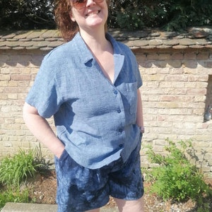 May include: A woman wearing a blue button-down shirt and blue denim shorts.