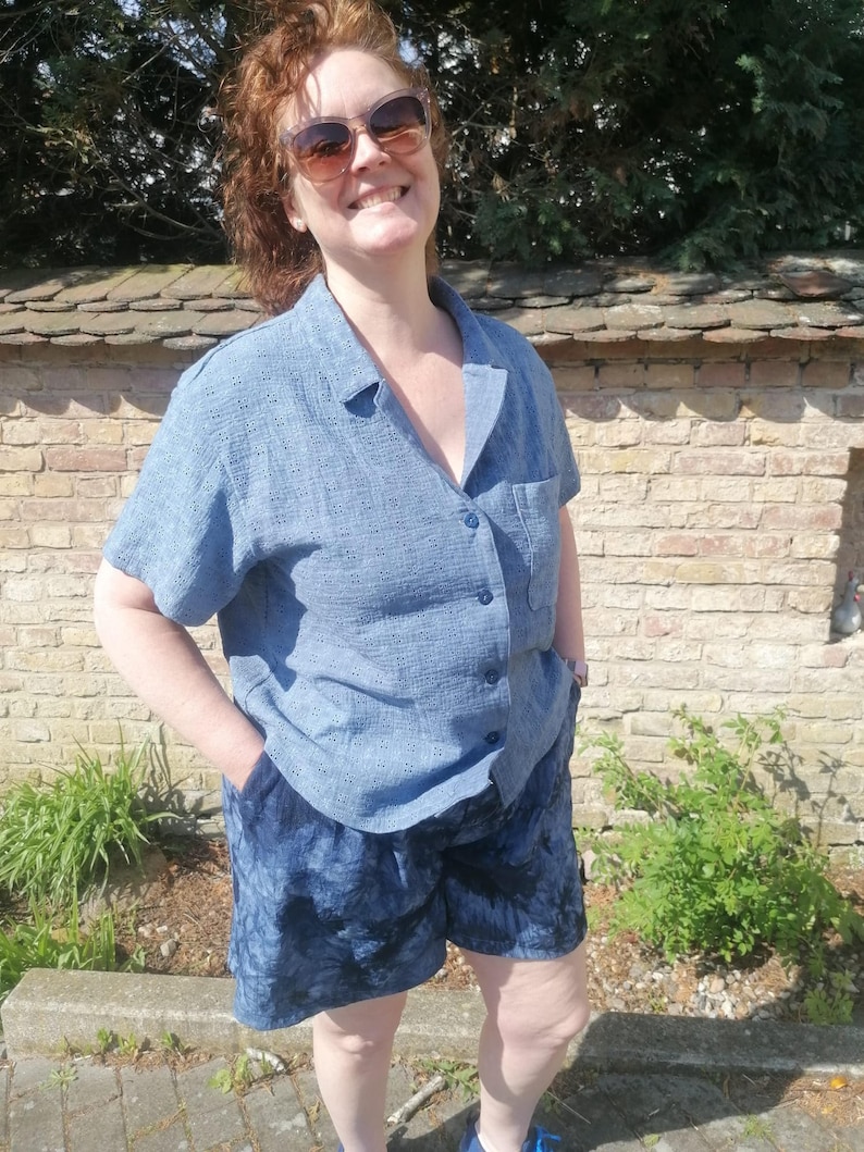 May include: A woman wearing a blue button-down shirt and blue denim shorts.