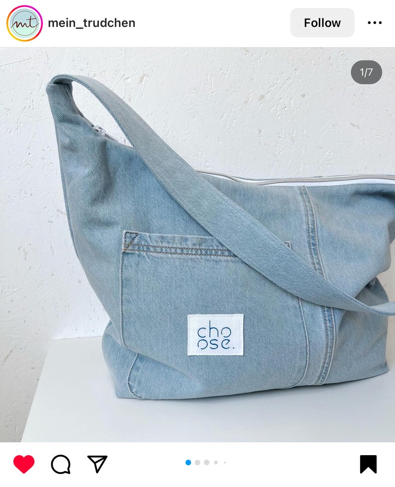 May include: A light blue denim tote bag with a white zipper and a white patch that says "choose." The bag has a long strap and a pocket on the front.