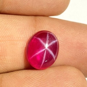 May include: A bright pink star ruby gemstone with a six-pointed star in the center.
