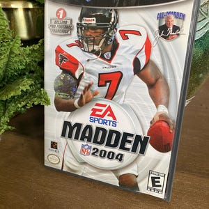 May include: Madden NFL 2004 video game case for Nintendo GameCube. The cover features a football player in a Falcons uniform, holding a football. The game is rated "Everyone" by the ESRB.