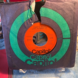 May include: A vintage vinyl record by The Sylvers, titled "That's What Love Is Made Of," in its original Capitol Records sleeve. The record label is orange with black text. The sleeve is purple with green circular accents.