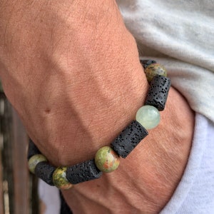 Op de afbeelding: Een armband met zwarte lavastenen kralen, groene en bruine jaspis kralen en een lichtgroene jade kraal.