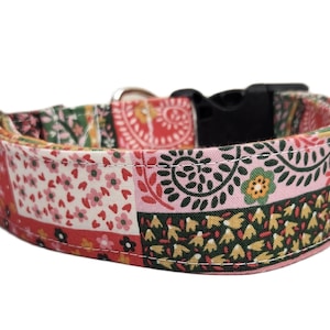 May include: A colorful dog collar with a patchwork design. The collar features a variety of patterns, including floral and paisley motifs, in shades of red, pink, green, and black. It has a black plastic buckle and silver metal hardware.
