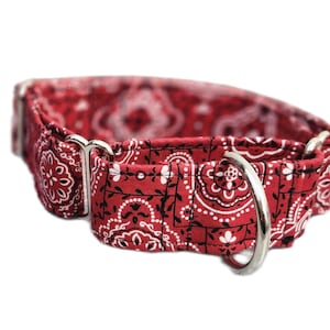 Op de afbeelding: Rode bandana-halsband voor honden met zilverkleurige metalen ring en hardware. De stof heeft een herhalend wit en zwart bloemenpatroon op een rode achtergrond. Ontworpen voor een comfortabele pasvorm.