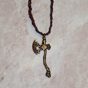 Bronze toned ax pendant on a hand-braided leather strap with 2 bronze beads braided in