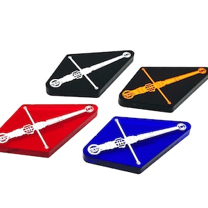 May include: Four diamond-shaped acrylic tokens with a white sword design. The tokens are black, red, blue, and orange.