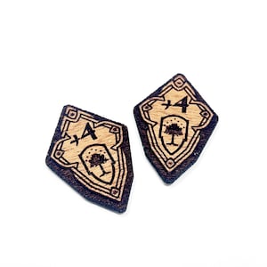 May include: Two wooden shield-shaped tokens with a tree and the text " +4" engraved on them.