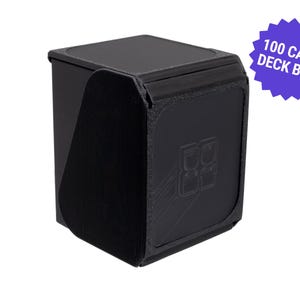 Op de afbeelding: Zwarte kaartenbox met een getextureerd oppervlak en een magnetische sluiting. De box heeft ruimte voor 100 kaarten en heeft een logo op de voorkant. Een paarse stersticker leest "100 CARD DECK BOX".