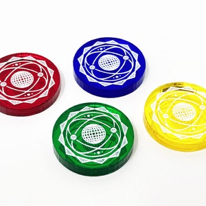 Könnte beinhalten: Vier runde Spielsteine mit einem weißen Atomdesign auf weißem Hintergrund. Die Steine sind rot, blau, grün und gelb.