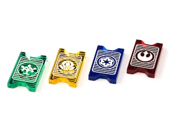 Peut inclure: Quatre pions de jeu en plastique avec différents symboles. Les pions sont vert, jaune, bleu et rouge. Les symboles sont un flocon de neige, un sabre laser, le symbole impérial et le symbole de l'Alliance rebelle.