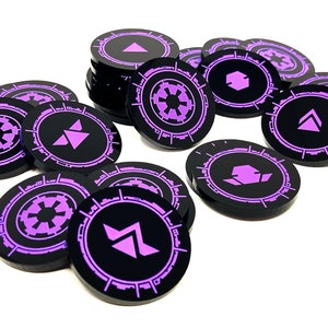 May include: A collection of black and purple game tokens with different symbols. The tokens are circular and have a raised edge. The symbols include a star, a triangle, and a square.