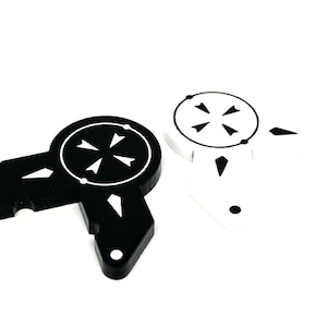 May include: Two plastic game pieces, one black and one white, with a circular design featuring a cross with four arrows pointing outward. The pieces are shaped like a rounded triangle with a small point on each side.